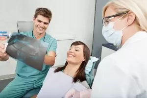 Woman getting a dental exam with dentist showing X-rays