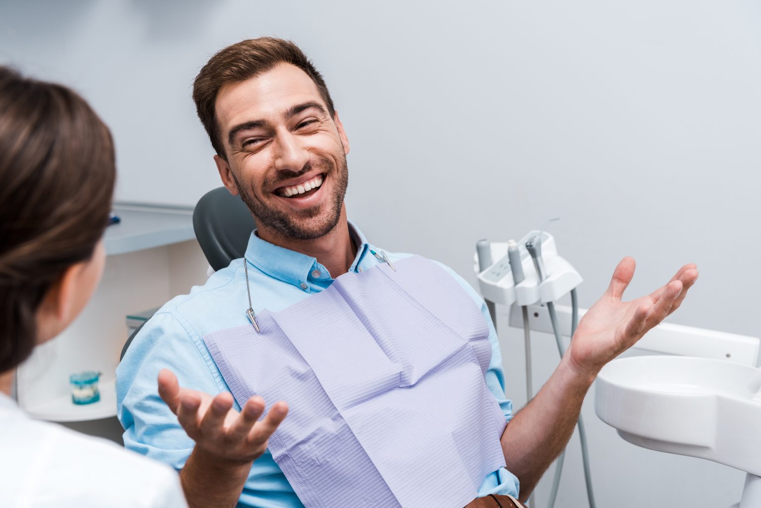 selective focus of happy patient gesturing and looking at dentist