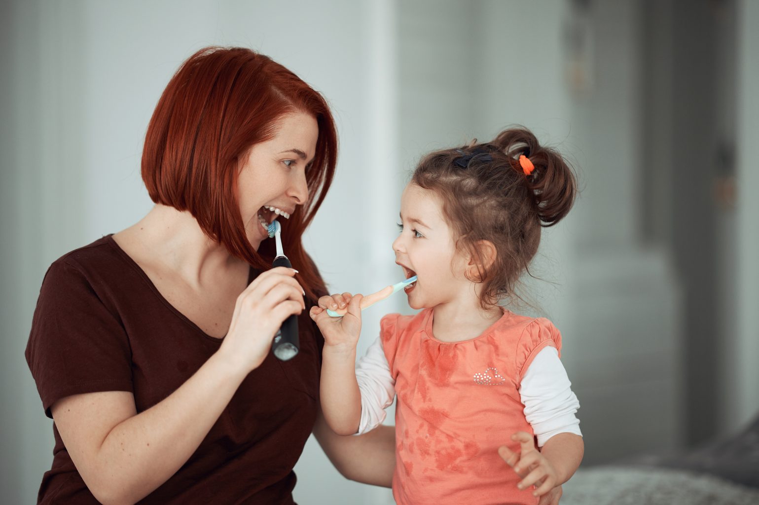 Redhead mother and baby girl indoors, brush their teeth, cleaning and routine photos