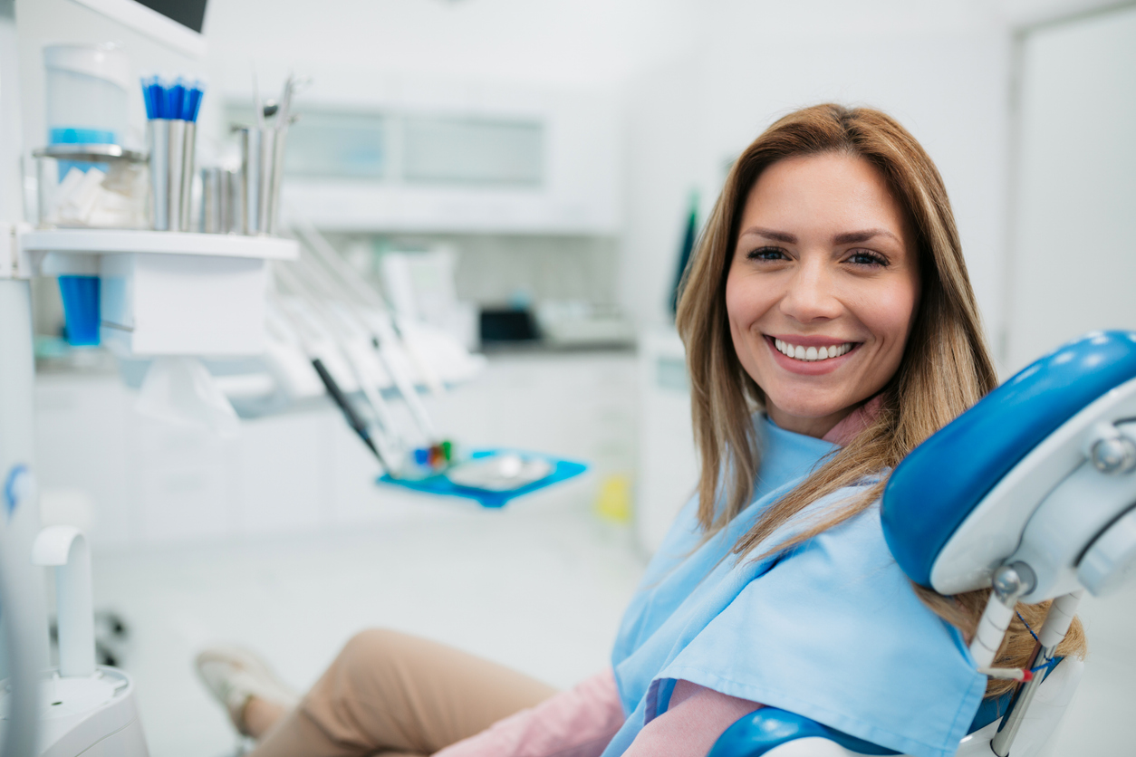 Happy woman visiting a dentist office in dental chair