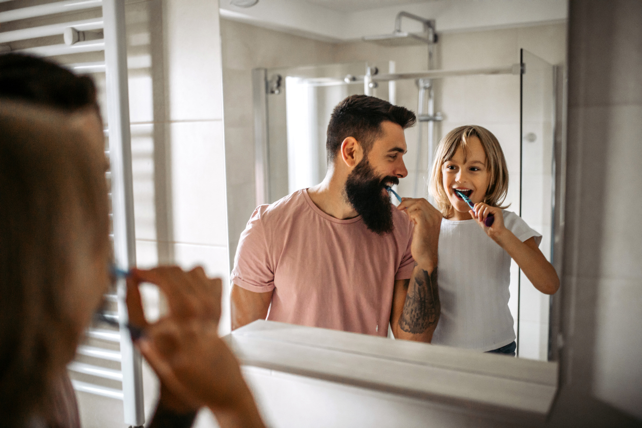 Father and daughter brushing their teeth in the bathroom