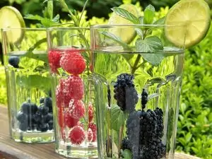 drinking glasses filled with water and fruit with a lime on top