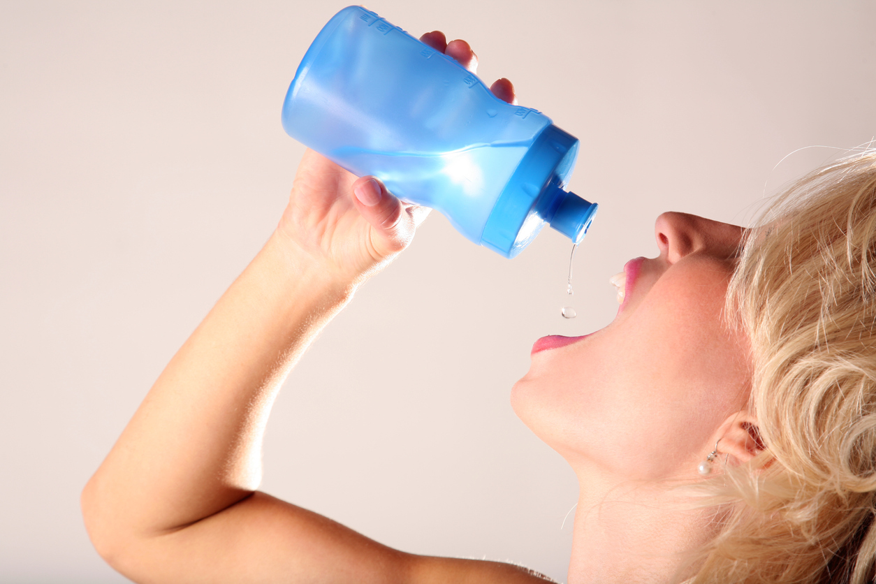 Female desperately drinks water out of a water bottle