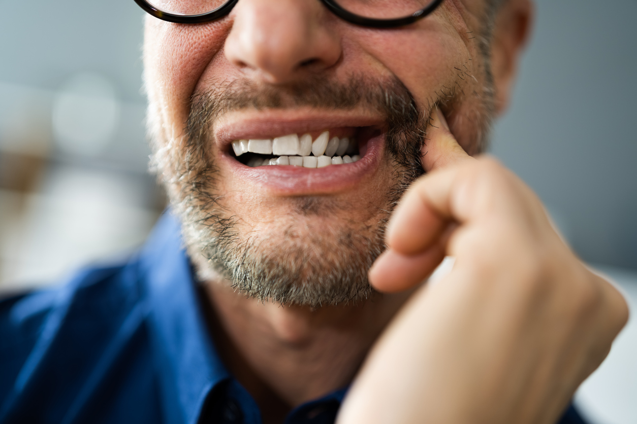 Man with a toothache pressing on cheek