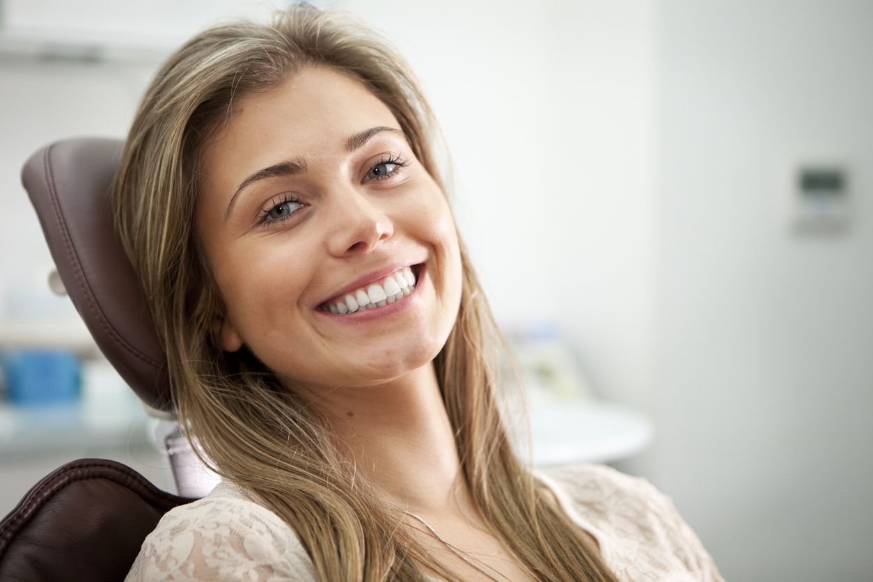 Happy female dental patient in dental chair
